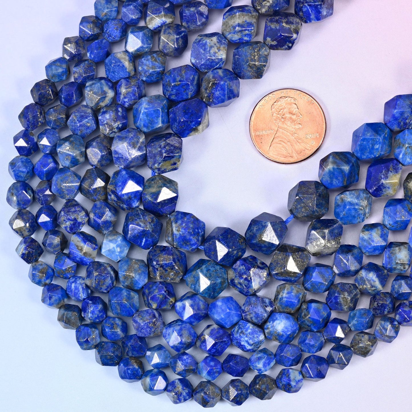 Blue Lapis Lazuli star cut beads with a US penny alongside for size reference, available in 6mm, 8mm and 10mm