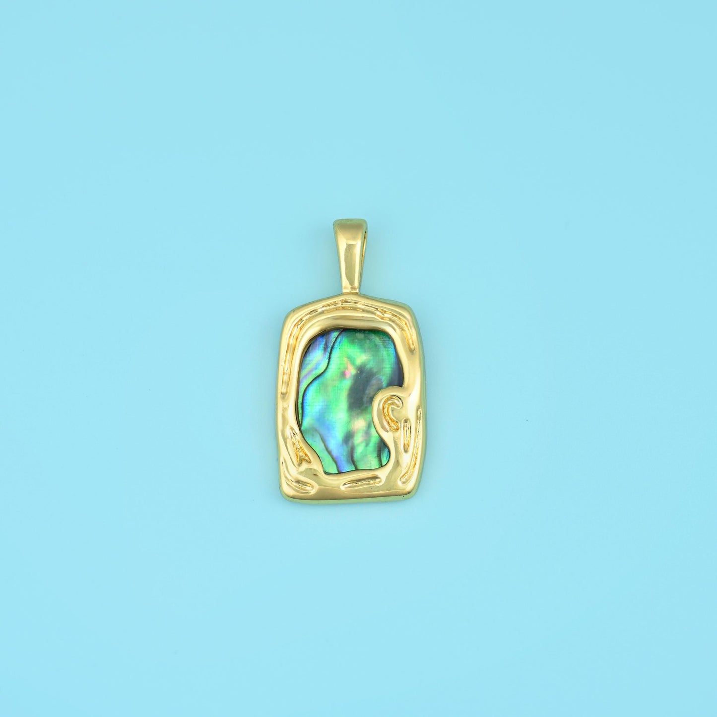 A slab of abalone shell flashing peacock green, blue, violet and rose, set inside a softly hammered rectangular gold-tone…