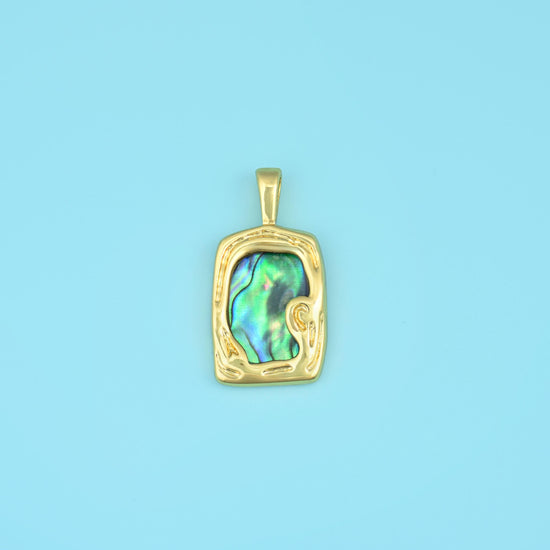 A slab of abalone shell flashing peacock green, blue, violet and rose, set inside a softly hammered rectangular gold-tone…