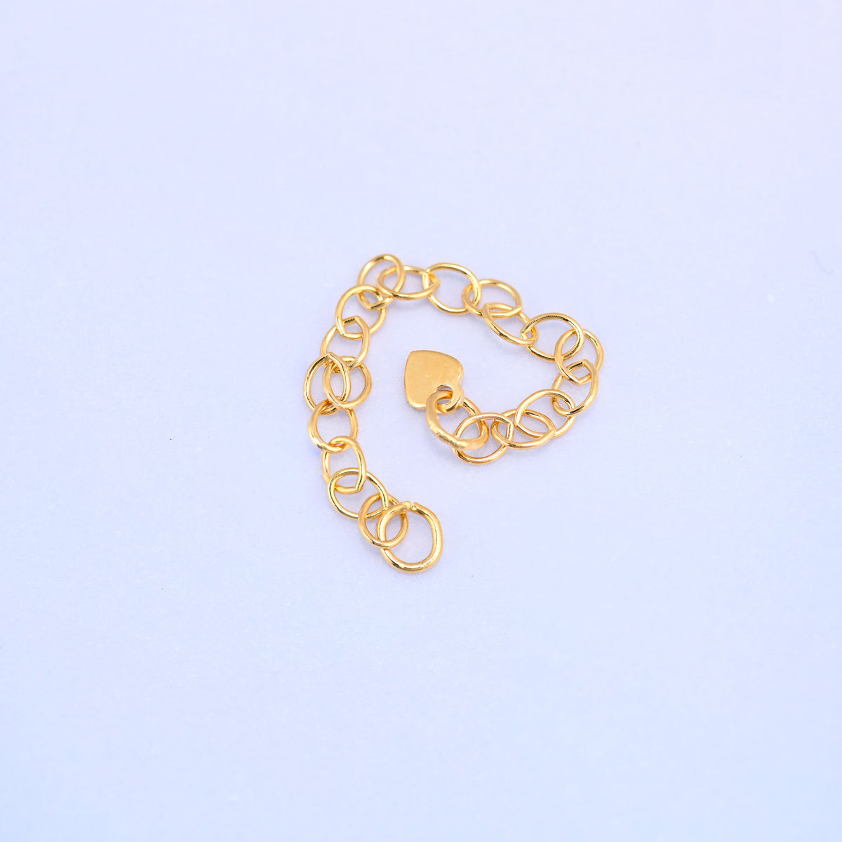 14K gold filled heart chain extender coiled loosely into a heart shape with the stamped heart charm resting in the center.