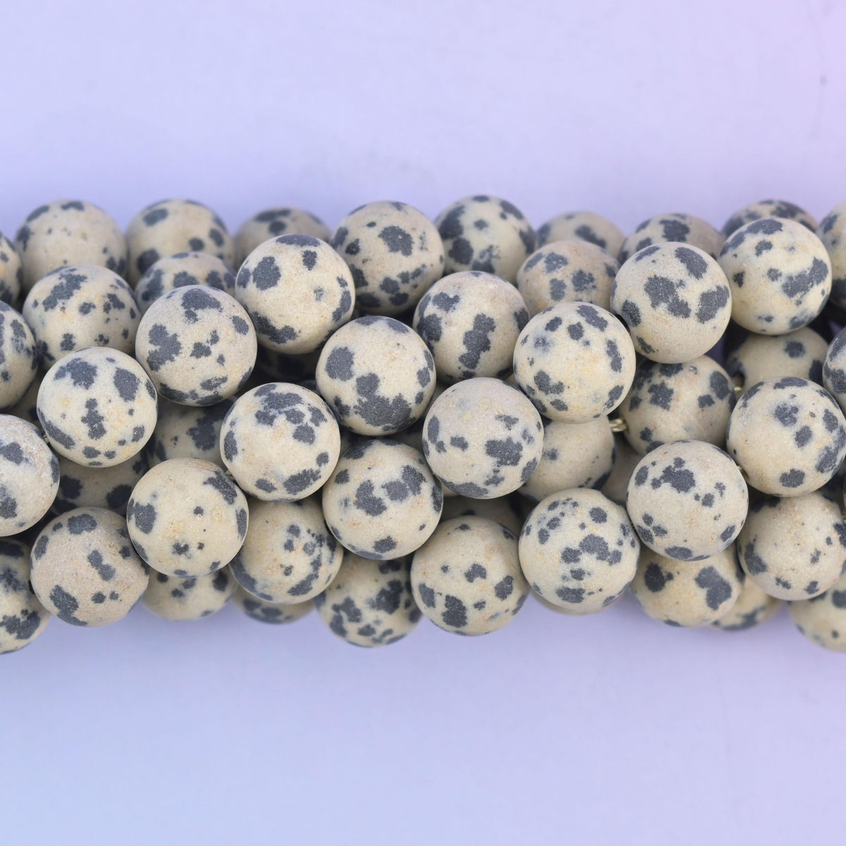 Round cut Dalmatian Jasper beads with a chalky frosted matte surface
