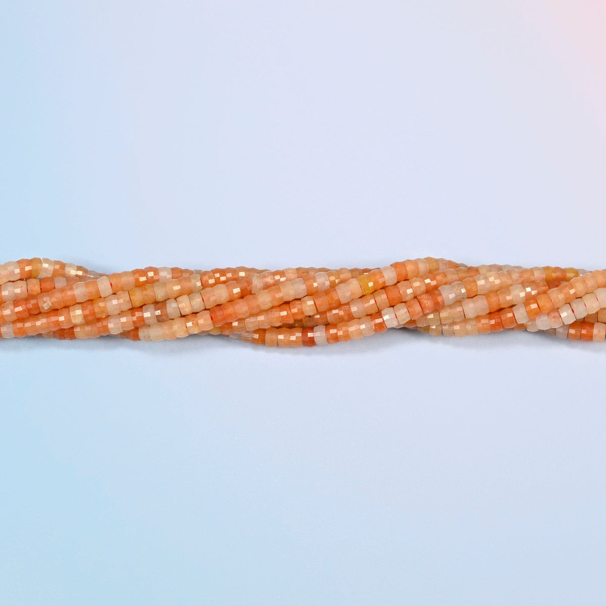 Strands of red aventurine faceted heishi disc beads twisted together in a horizontal row