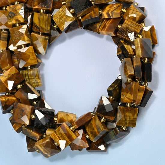 Natural tiger eye faceted flat square beads coiled into overlapping loops, whole strands of warm golden brown stone