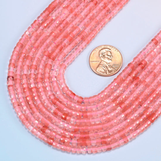 Close view of melon quartz faceted heishi disc strands curving beside a US penny for scale