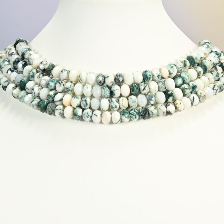 Tree agate faceted rondelle strands arranged as a layered collar on a white display bust, white and green beads across the neck