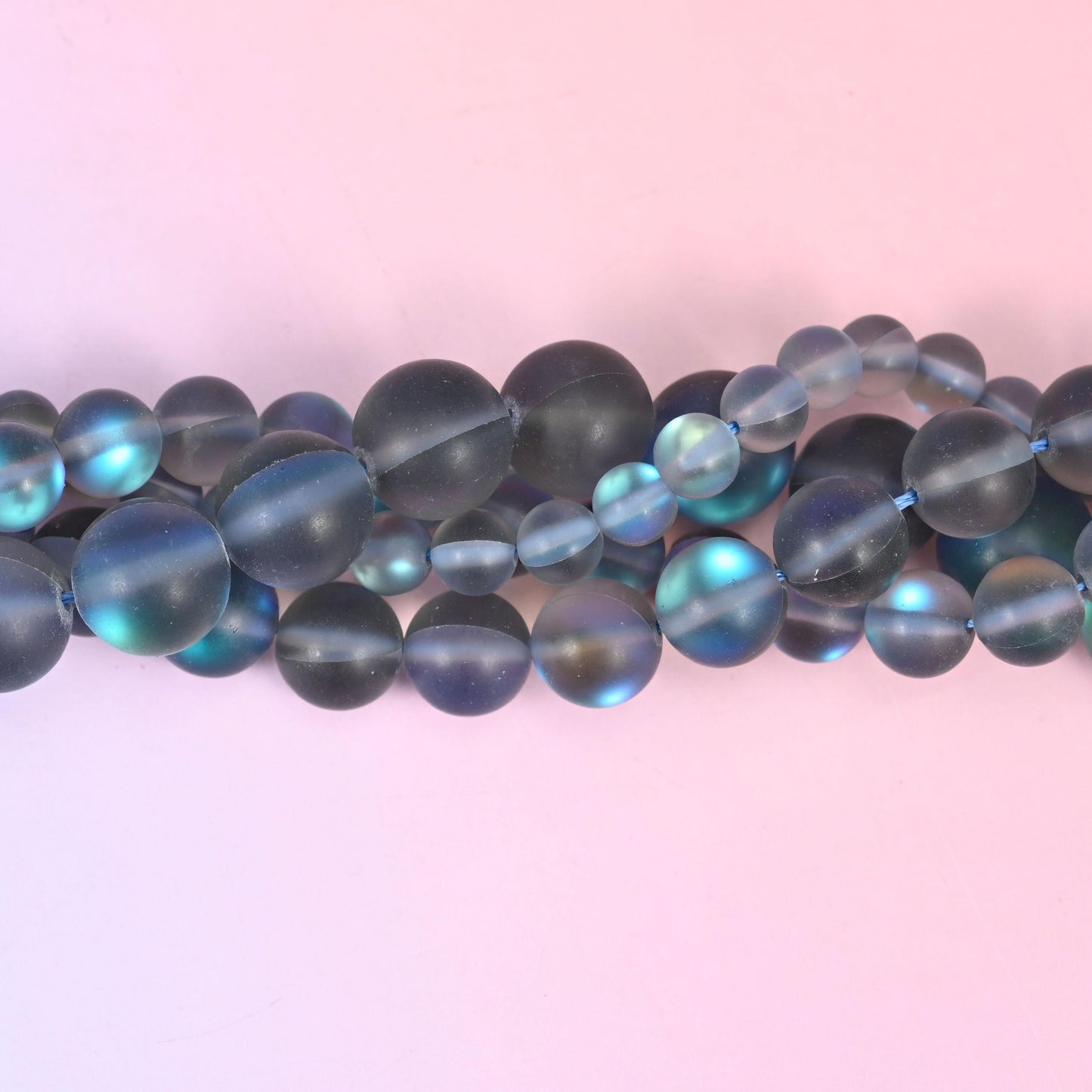 Frosted smoke grey glass beads with a soft sanded finish and aurora shimmer
