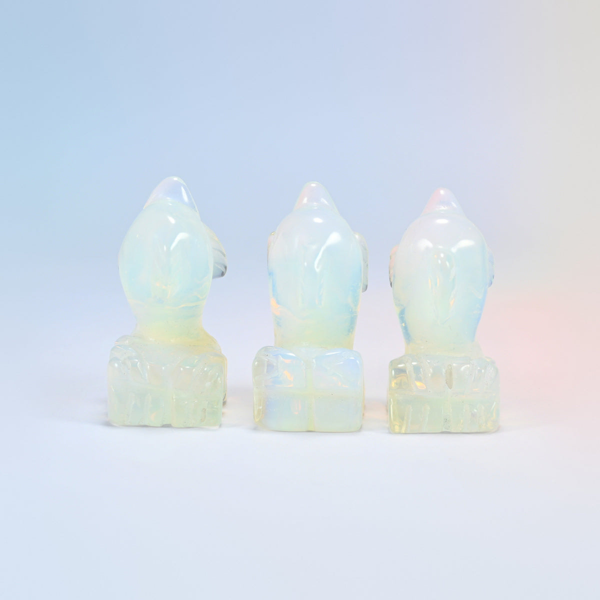 Back view of three opalite dolphin carvings showing the carved wave base