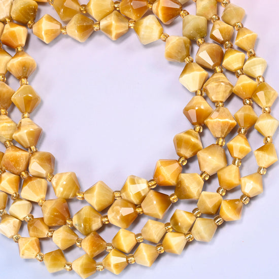 Gold tiger eye bicone beads formed into a wide open ring, the chatoyant sheen catching along the ridge of each facet.