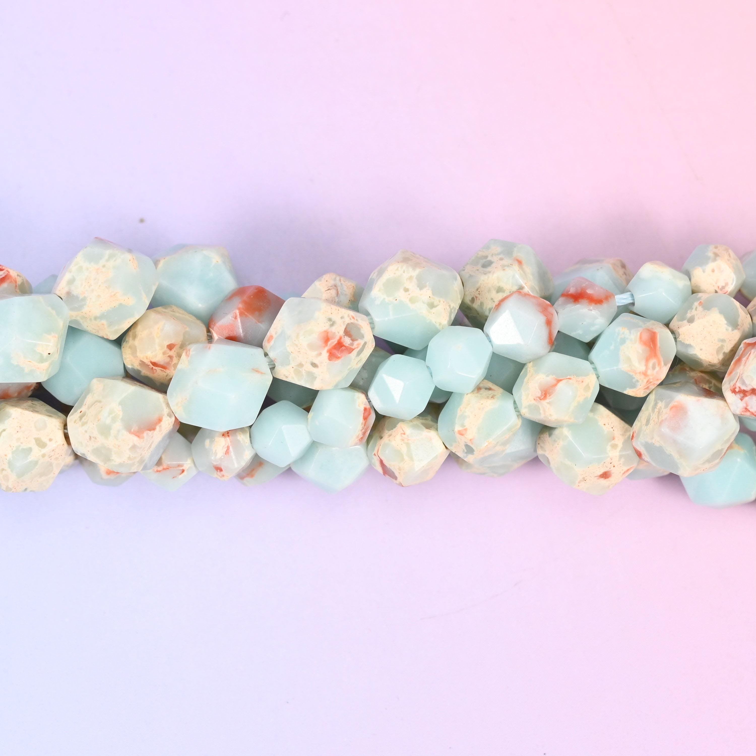 Powder-blue star cut beads flecked with ivory cream and rust terracotta, each faceted plane picking up a different shade so the strand reads soft blue from across the room and mottled up close.