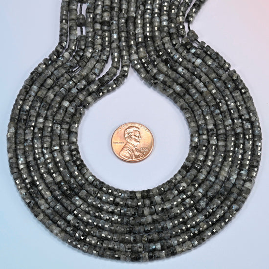 Black labradorite faceted heishi disc strands formed into a teardrop loop around a US penny for scale