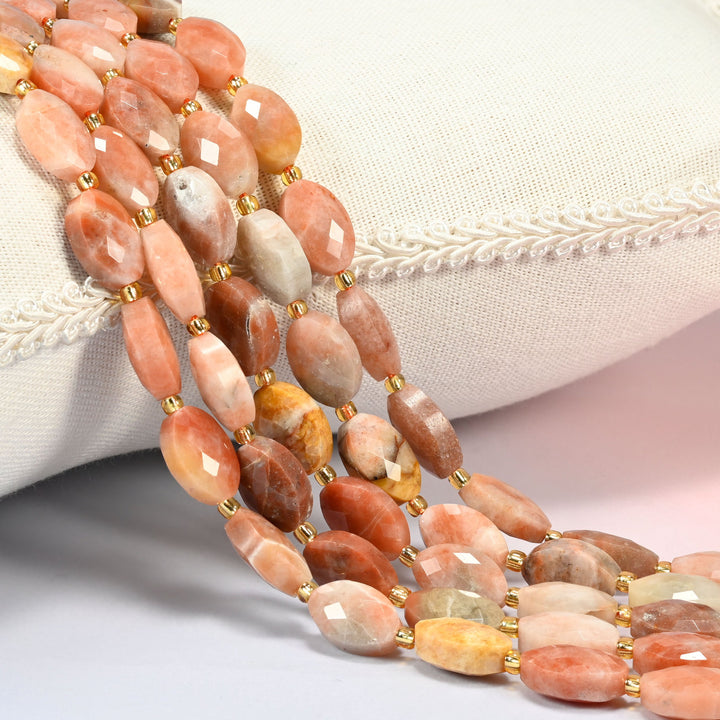 Red crazy agate faceted flat oval beads 9x14mm with small gold seed bead spacers, several strands draped over a white cushion