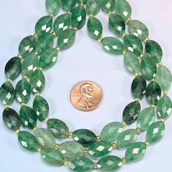 Green strawberry quartz faceted flat oval strands formed into a teardrop loop around a US penny for scale