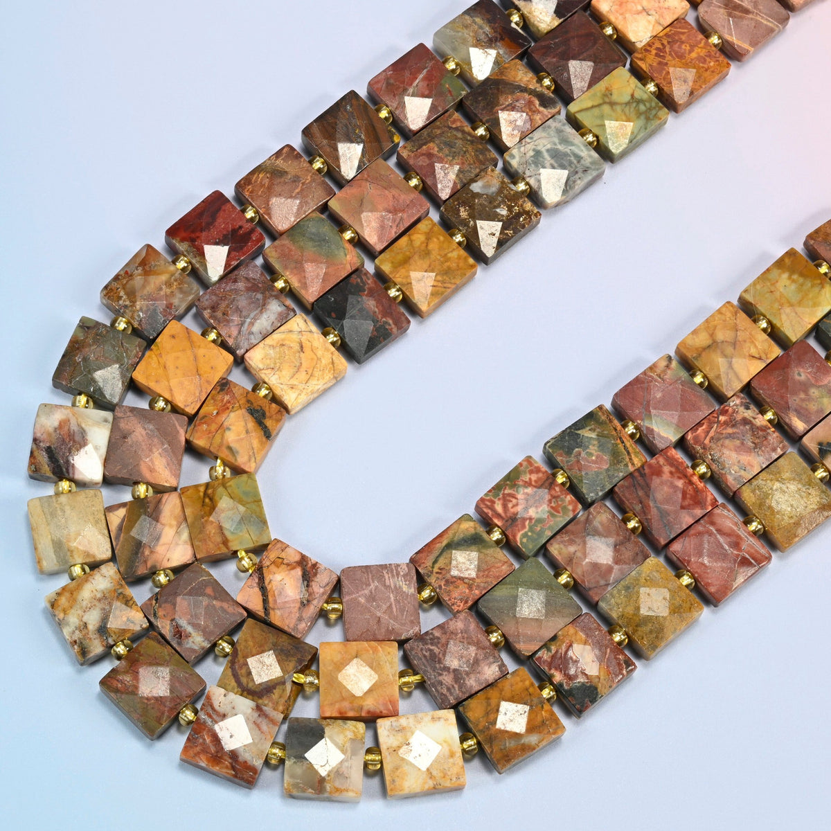 Natural red howlite faceted flat square beads in several strands curved into a wide U, brick red, olive green and tan stone