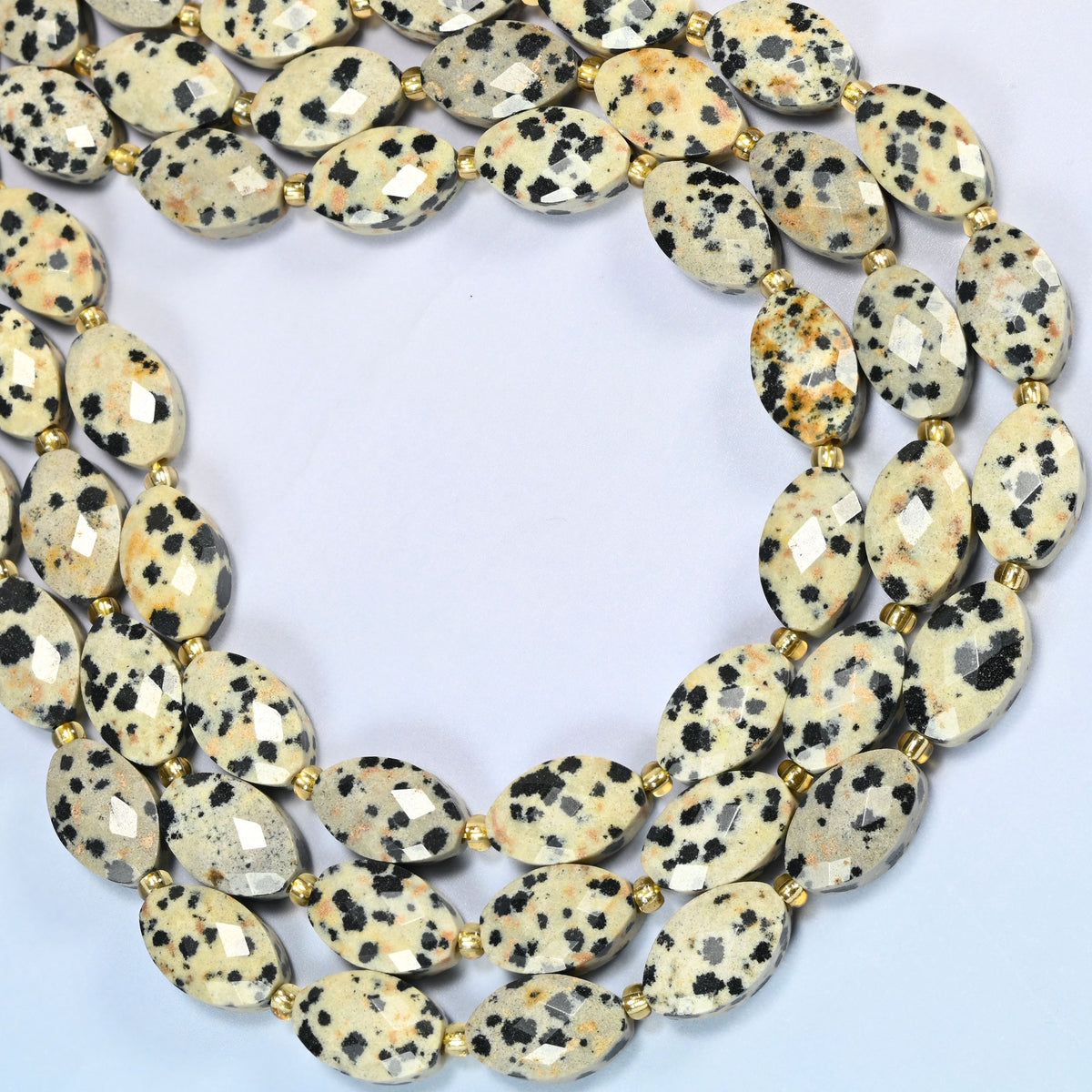 Dalmatian jasper faceted flat oval beads curved into an open loop, cream and black spotted stone