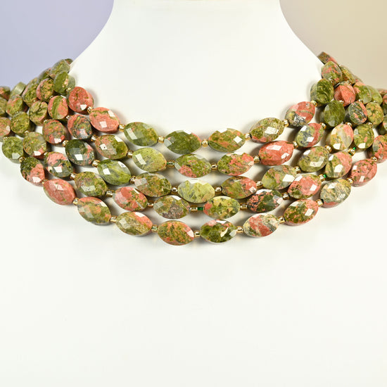 Unakite faceted flat oval strands arranged as a layered collar on a white display bust, green and pink beads across the neck