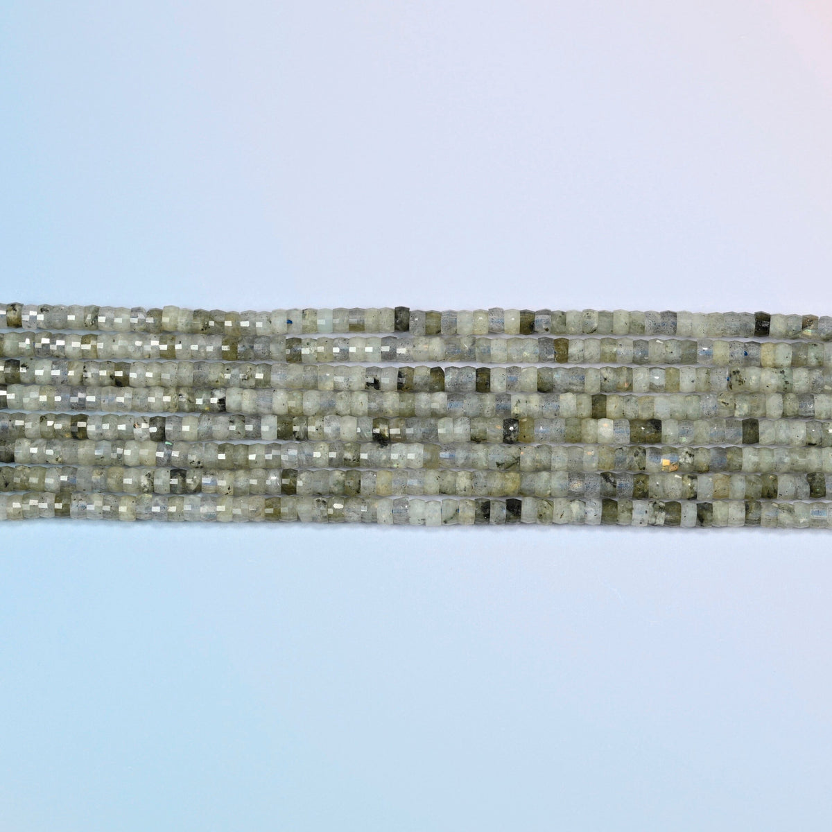 Several strands of white labradorite faceted heishi disc beads laid in straight rows