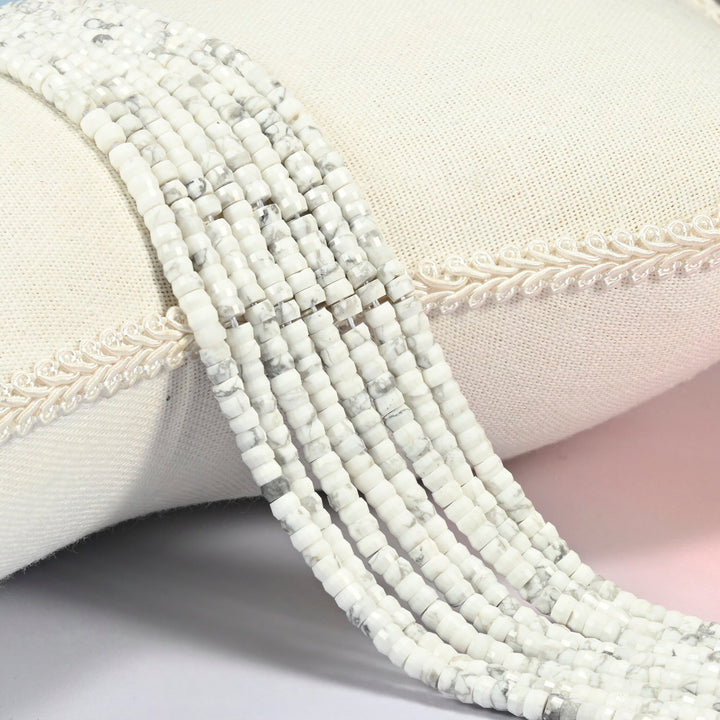 White howlite faceted heishi disc beads 2x4mm, several strands draped over a white cushion