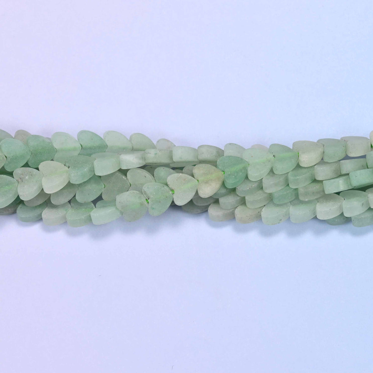 Matte green aventurine flat heart beads in soft sage and mint green under a chalky frosted matte surface.