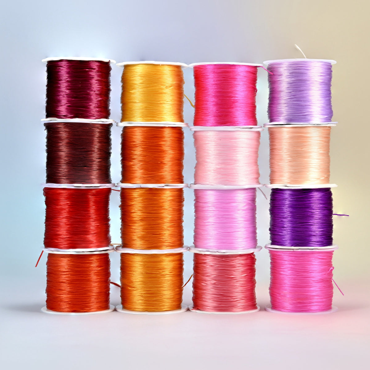 Sixteen rolls of 0.7-0.8mm elastic stretch string in warm colors: wine red, brown, red, orange, golden yellow, pink, peach, lavender and purple