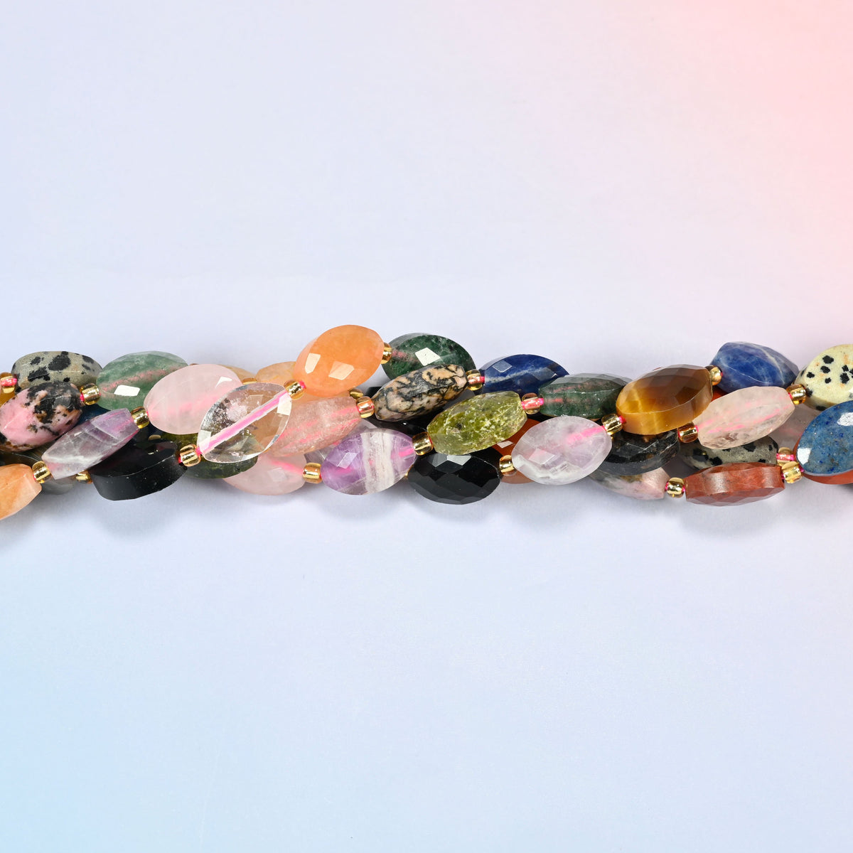 Strands of assorted gemstone faceted flat oval beads twisted together in a horizontal row