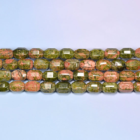 Close-up rows of faceted Unakite barrel beads laid flat, showing the mix of olive green and salmon pink patches.