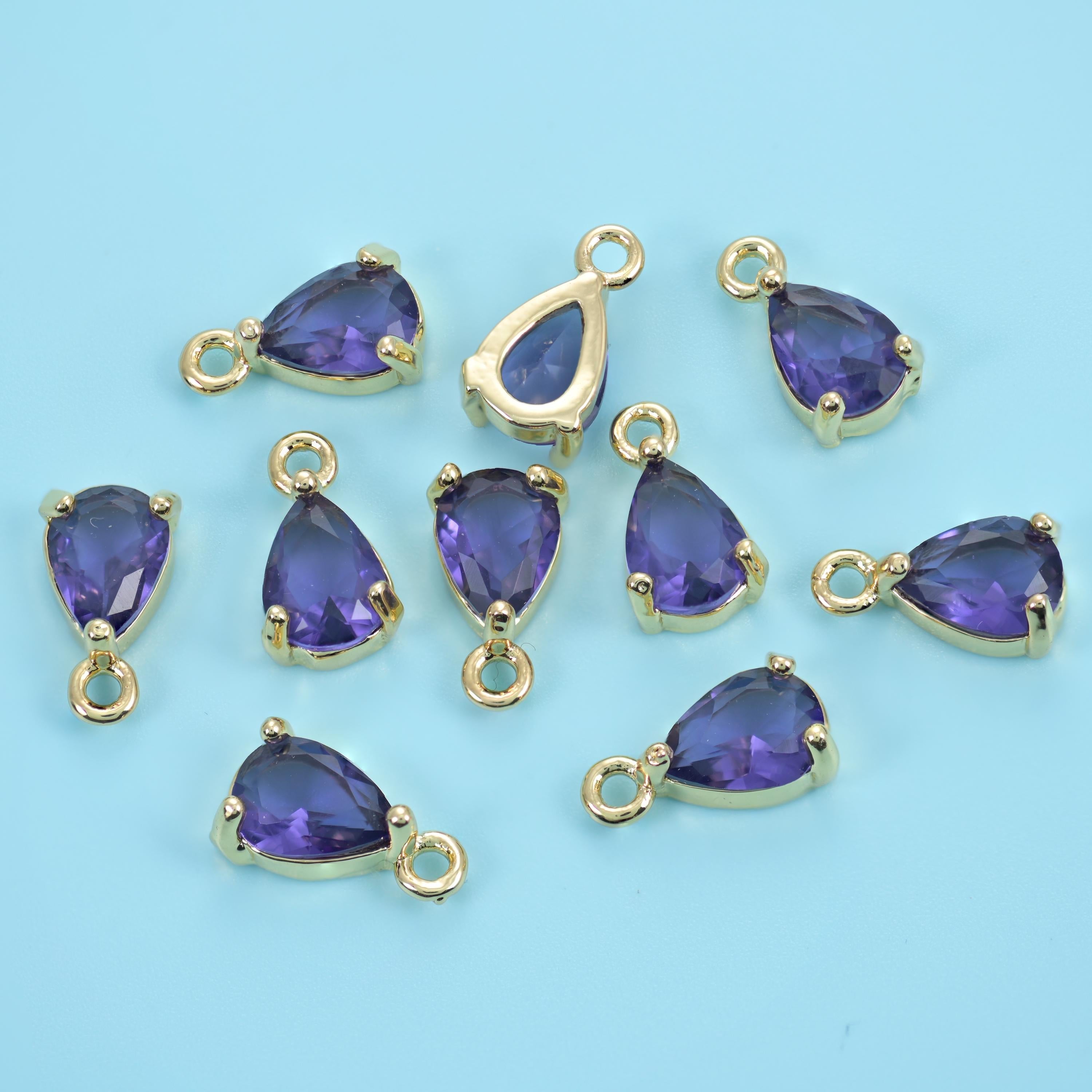 A pear-cut zircon held in a slim gold prong setting with a ring at the point, faceted right through so light passes clean…