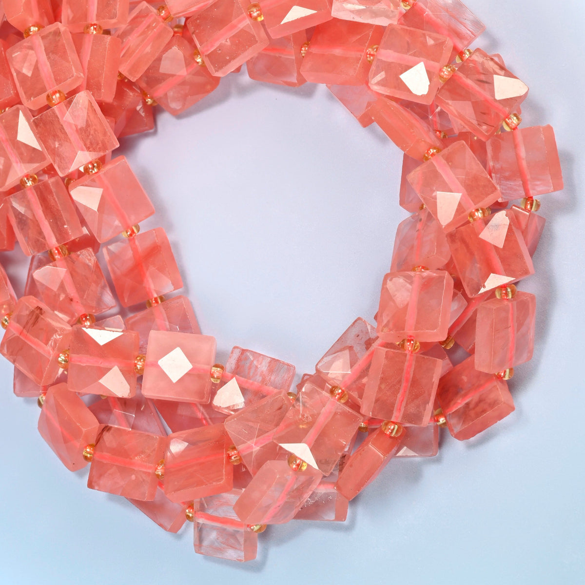 Melon quartz faceted flat square beads coiled into overlapping loops, whole strands of bright pink glass