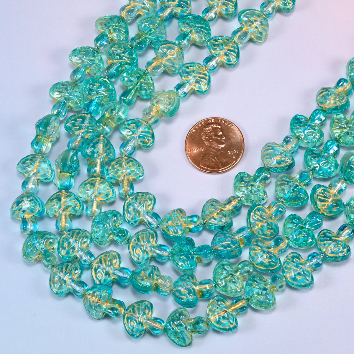Aqua gold flat mushroom glass beads laid in a narrow chevron, the two limbs running close together down to a point.
