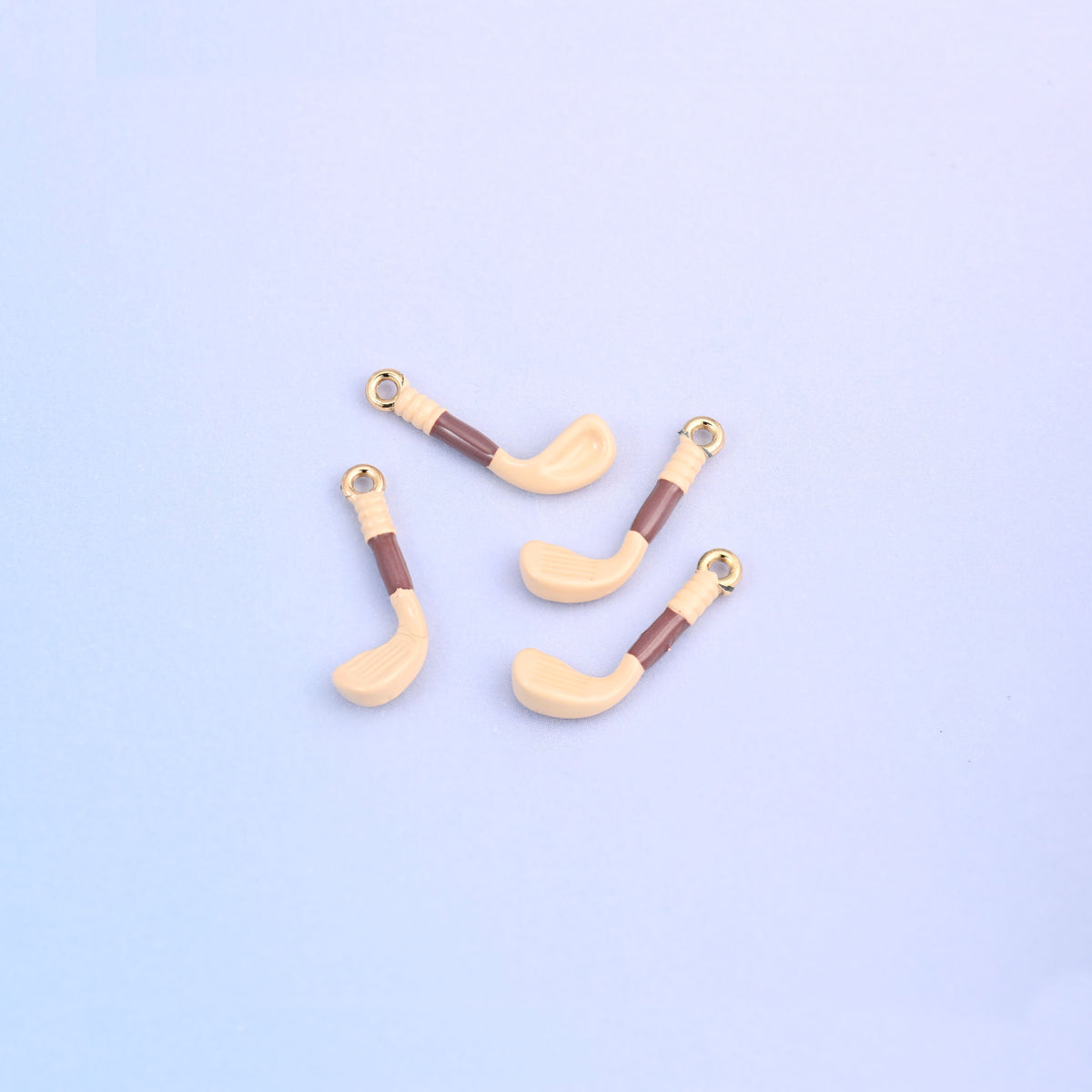 Four light orange golf club charms with brown enamel grips.