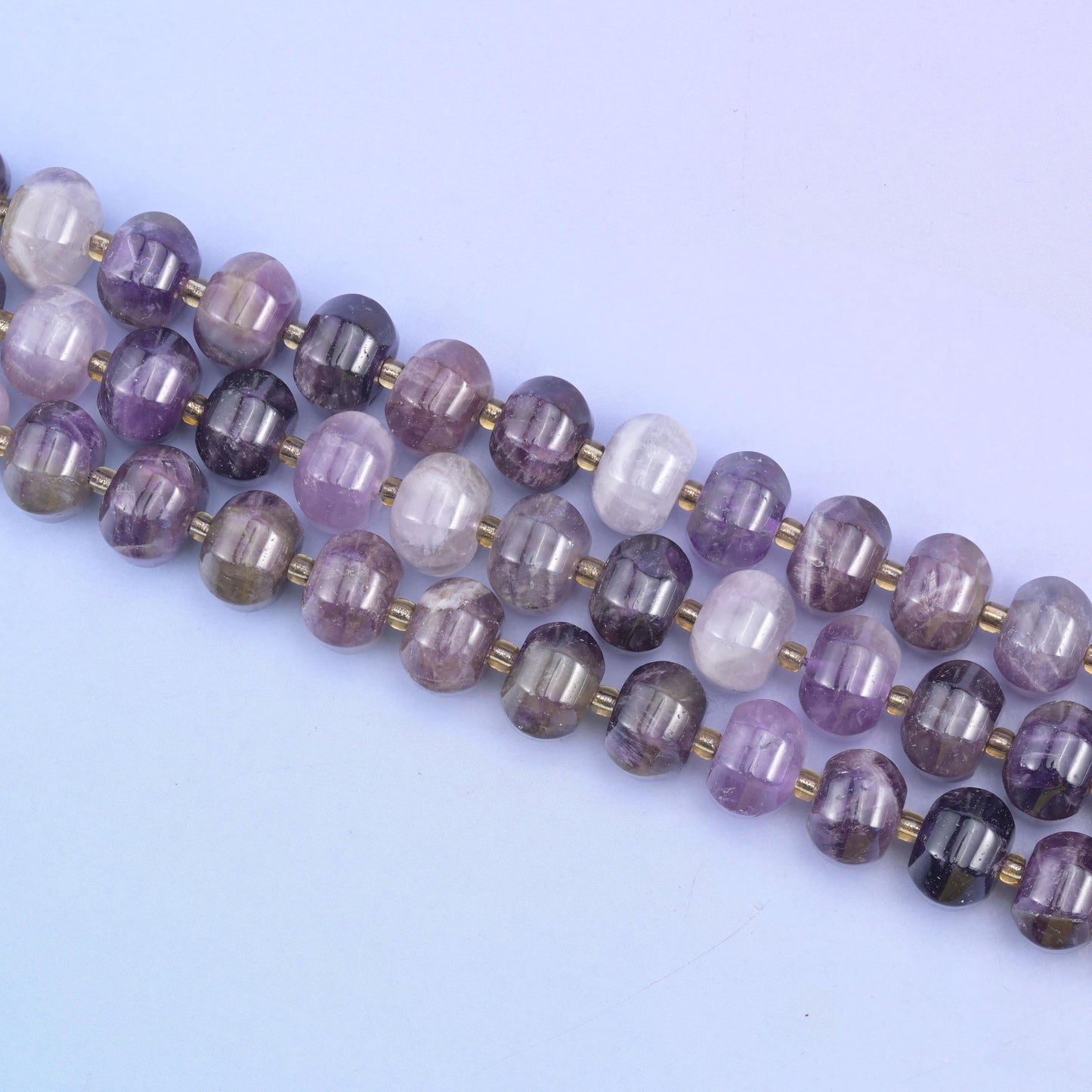 Three strands set on a diagonal, brass discs marking the join between each grooved bead