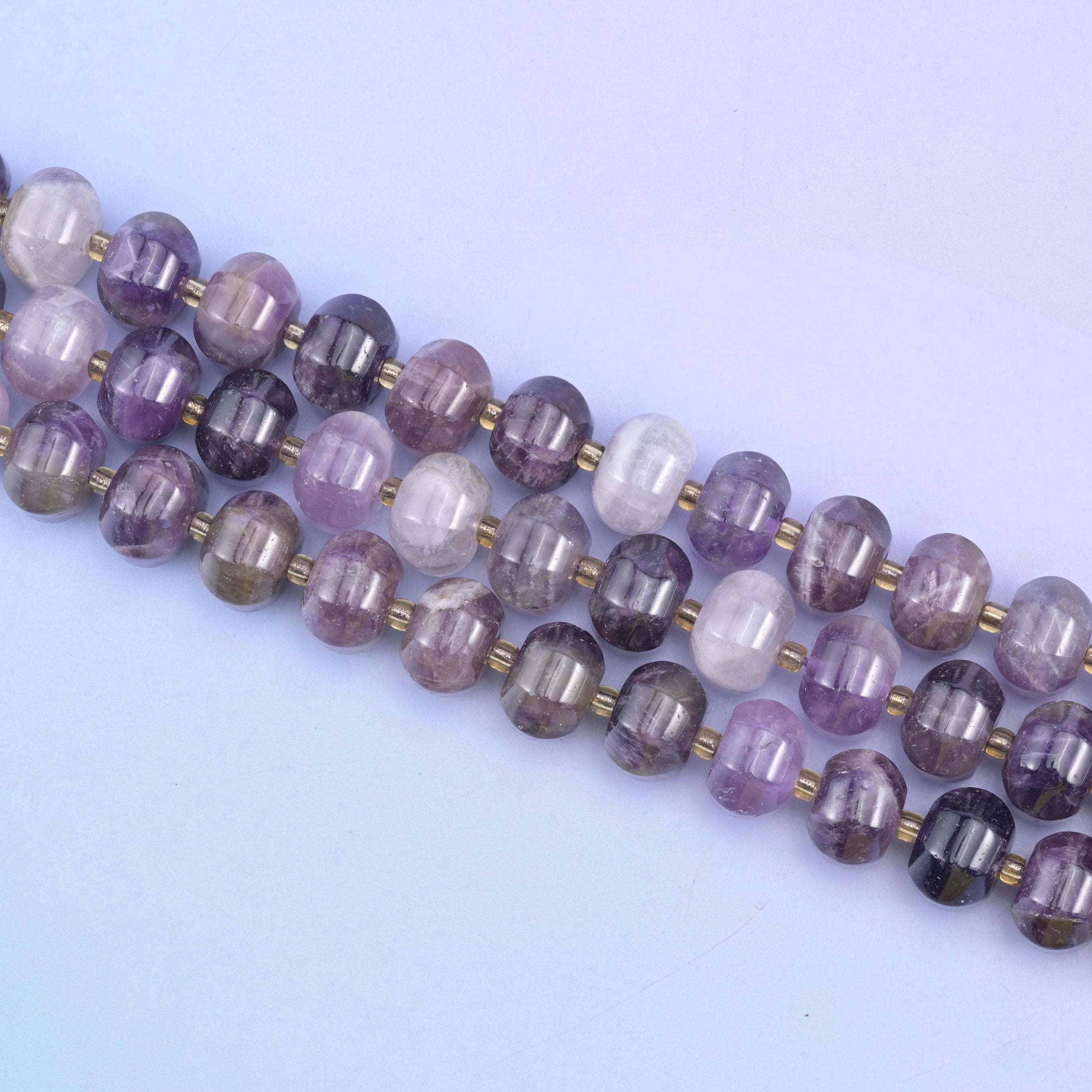 Three strands set on a diagonal, brass discs marking the join between each grooved bead