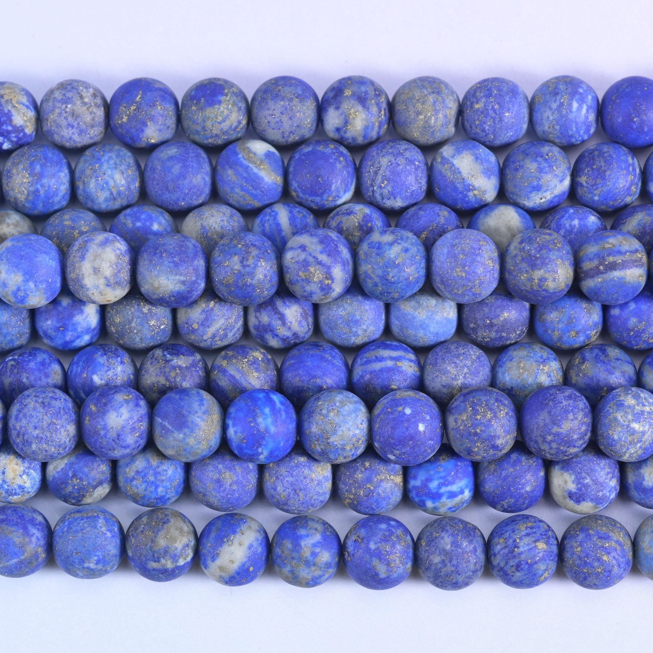 Deep denim blue under a dry frosted matte surface, flecked with tiny gold pyrite and streaked with pale grey calcite