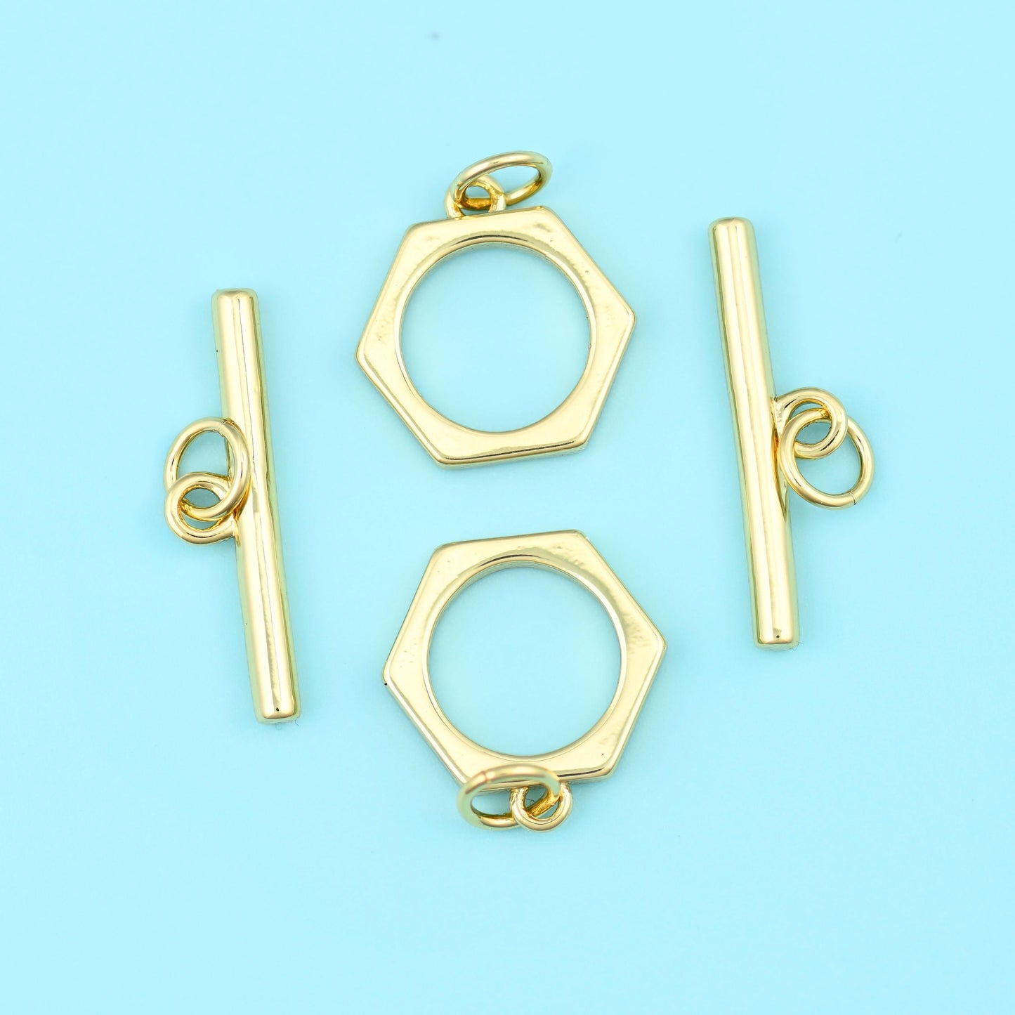A crisp six-sided ring paired with a smooth straight bar, both carrying a warm satin 18K gold filled finish over brass, and…