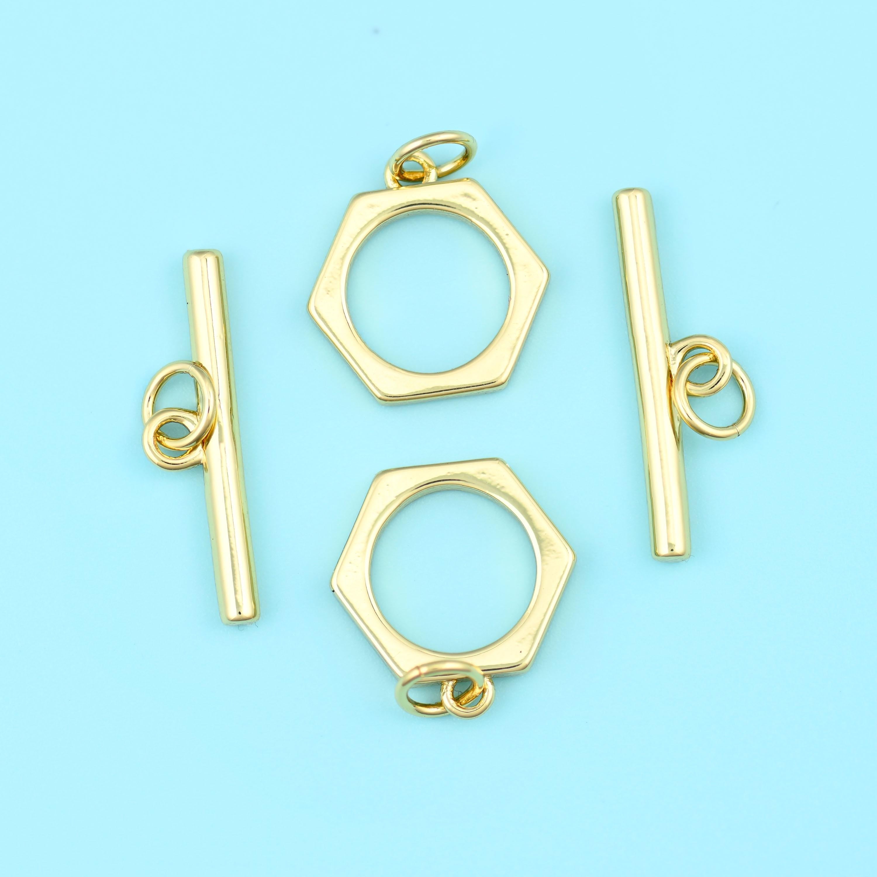 A crisp six-sided ring paired with a smooth straight bar, both carrying a warm satin 18K gold filled finish over brass, and…