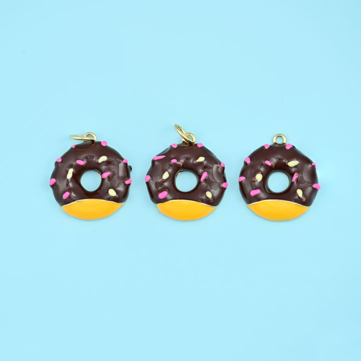 Sprinkle donut charms in chocolate brown icing with a golden glazed lower half, three charms in a row with pastel sprinkles.