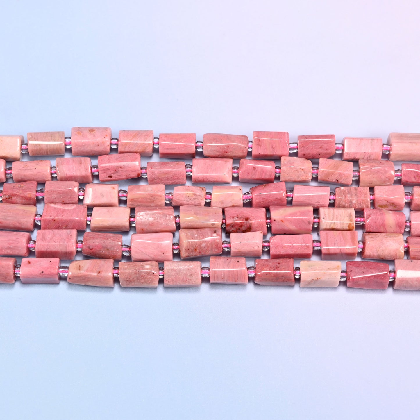 Side view of Pink Rhodonite faceted tube beads laid straight in two rows, showing the flat polished planes and short irregular lengths
