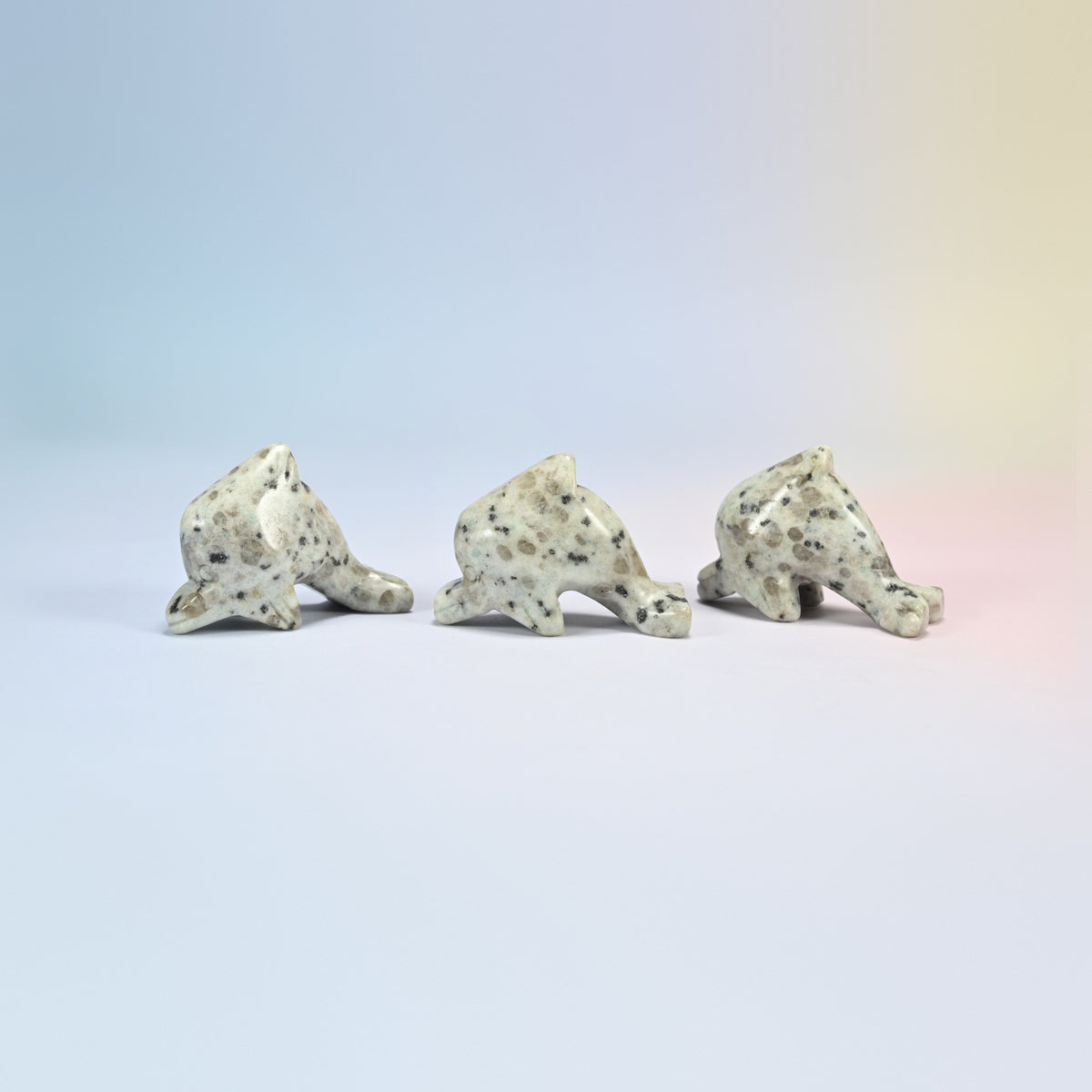Three kiwi jasper dolphin crystal carvings, cream and light green natural stone with dark spots