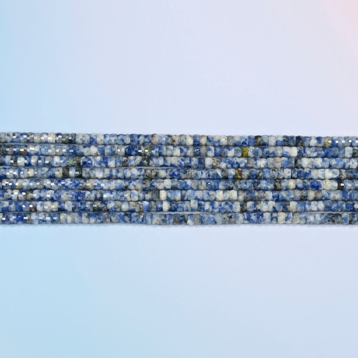 Several strands of blue spot jasper faceted heishi disc beads laid in straight rows