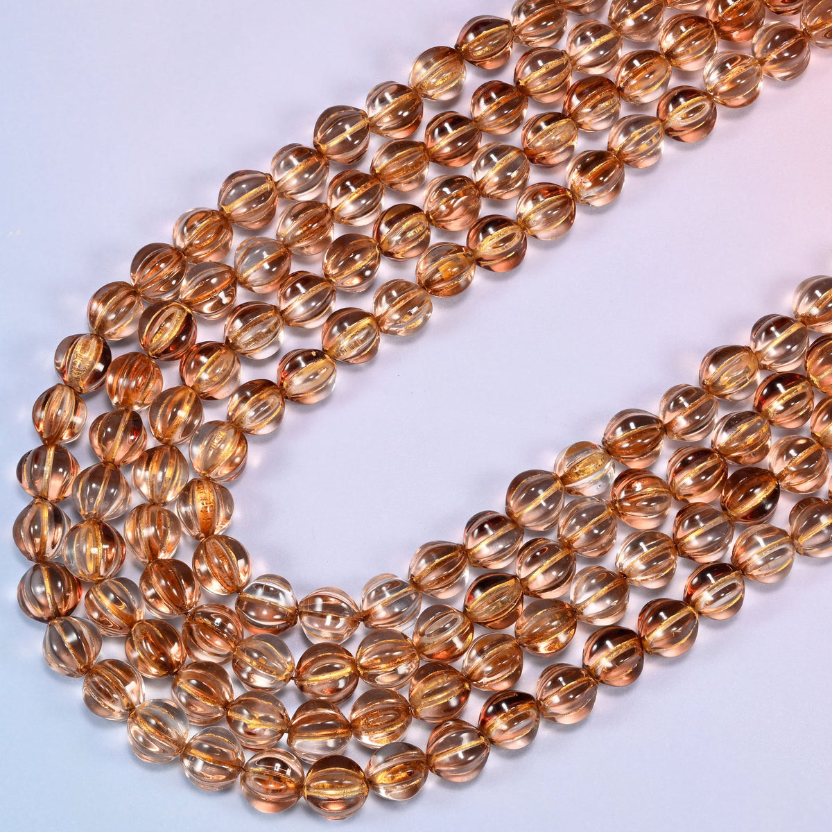 Brown pumpkin glass beads, several strands laid in a wide sweeping curve across the frame.