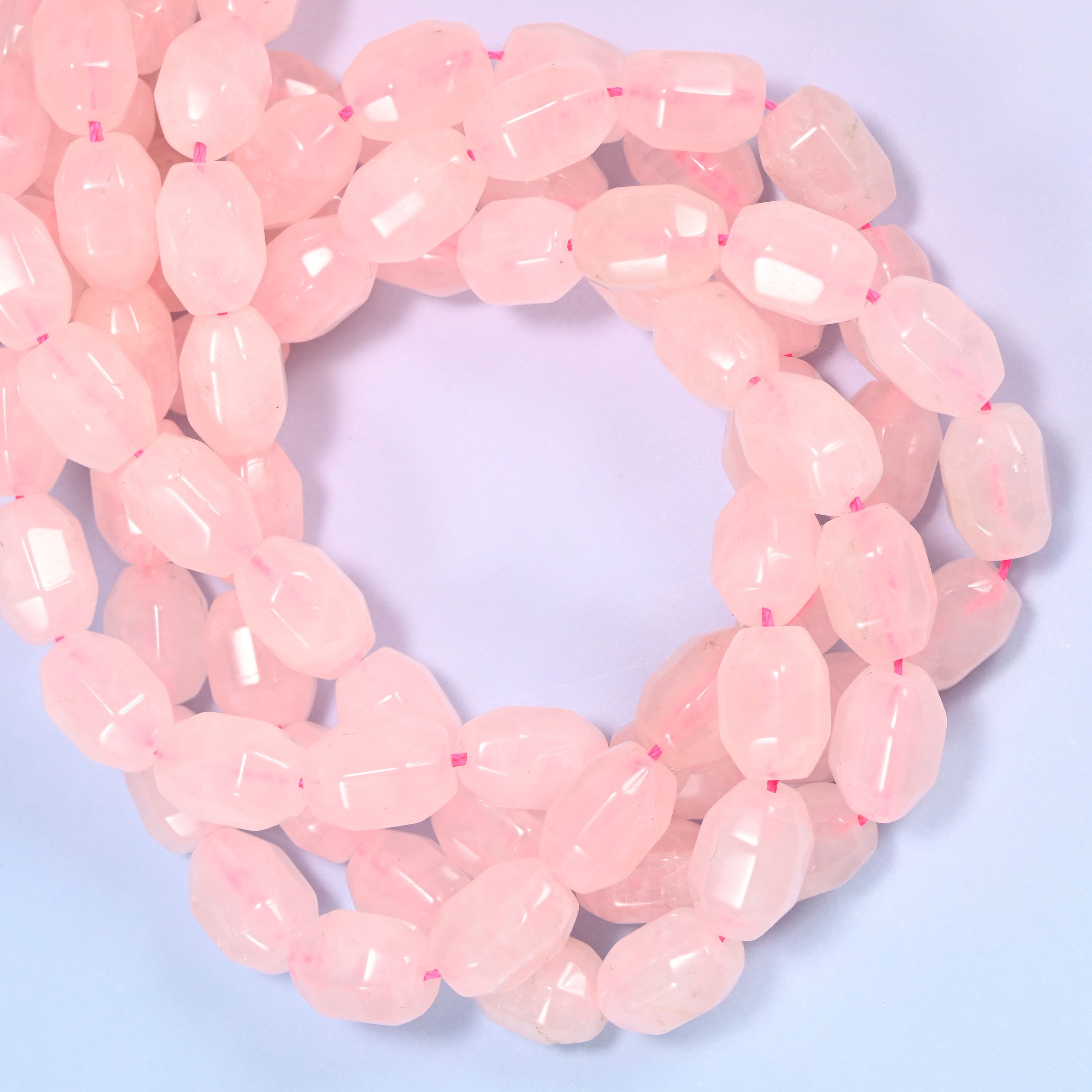 Wide circular coil of Rose Quartz faceted barrel beads on a light lavender and pink