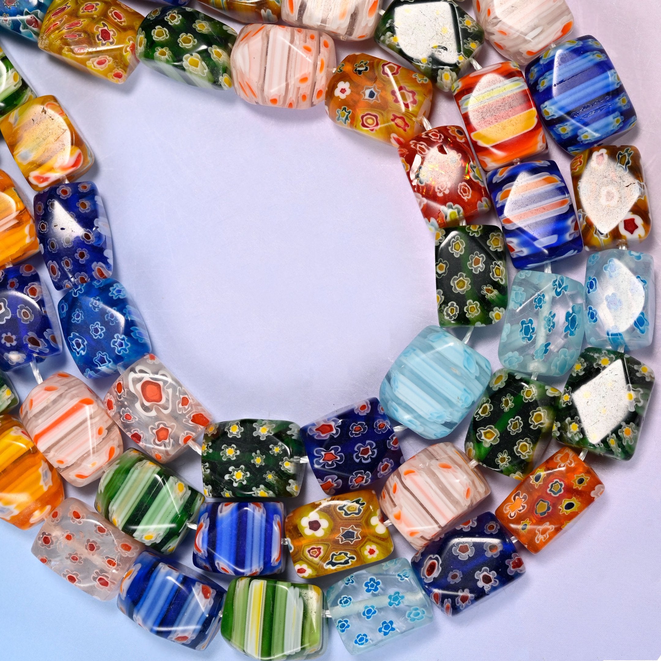 Millefiori cuboid beads with the corners cut into flat facets.