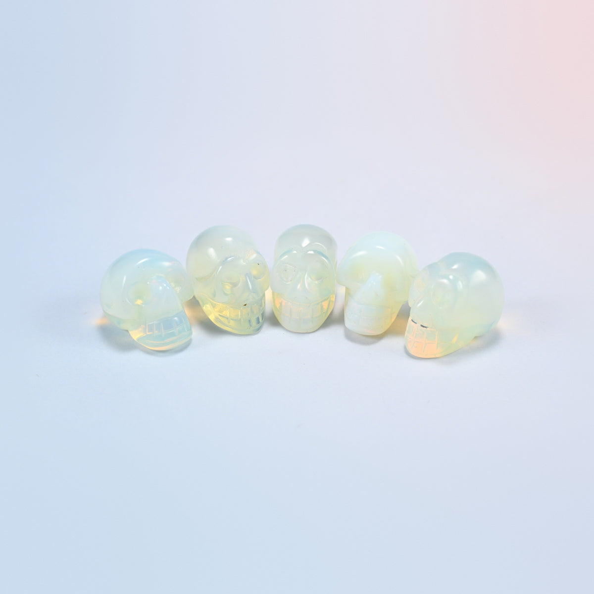 1 inch skull crystal carving in opalite, milky white man-made glass with a blue glow