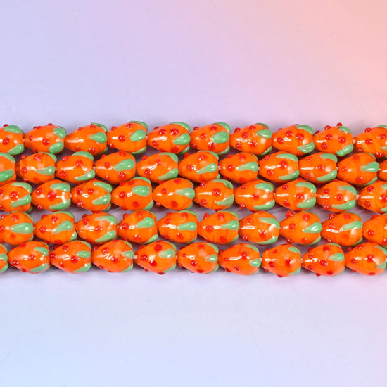 Glossy tangerine orange strawberry glass beads with red seed dots and a green leaf cap