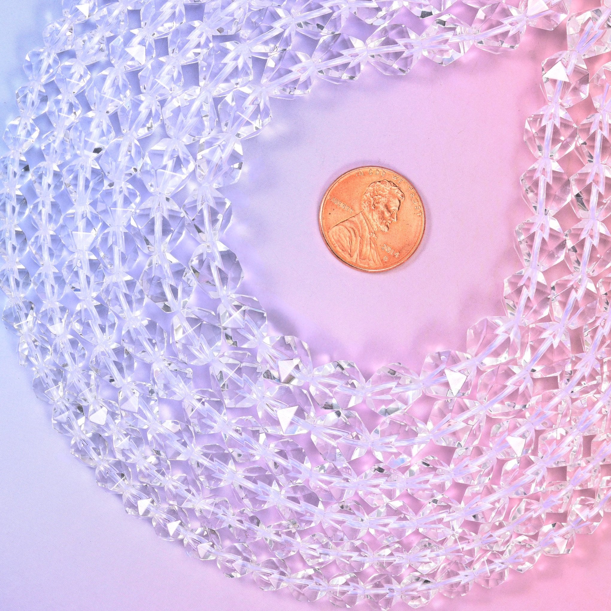 Clear Quartz diamond star cut beads coiled around a US penny for size reference