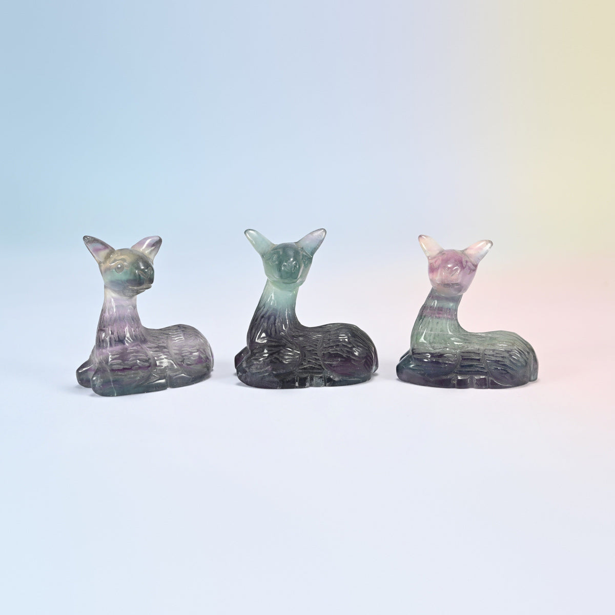 Three 2 inch natural rainbow fluorite deer crystal carvings, resting fawns in purple and green banding
