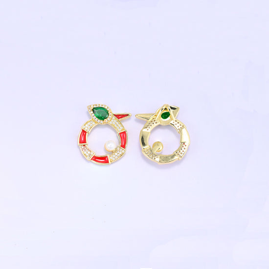 Round snake charm shown front and back, the red enamel and zircon face beside the plain gold reverse of a second piece, both standing upright.