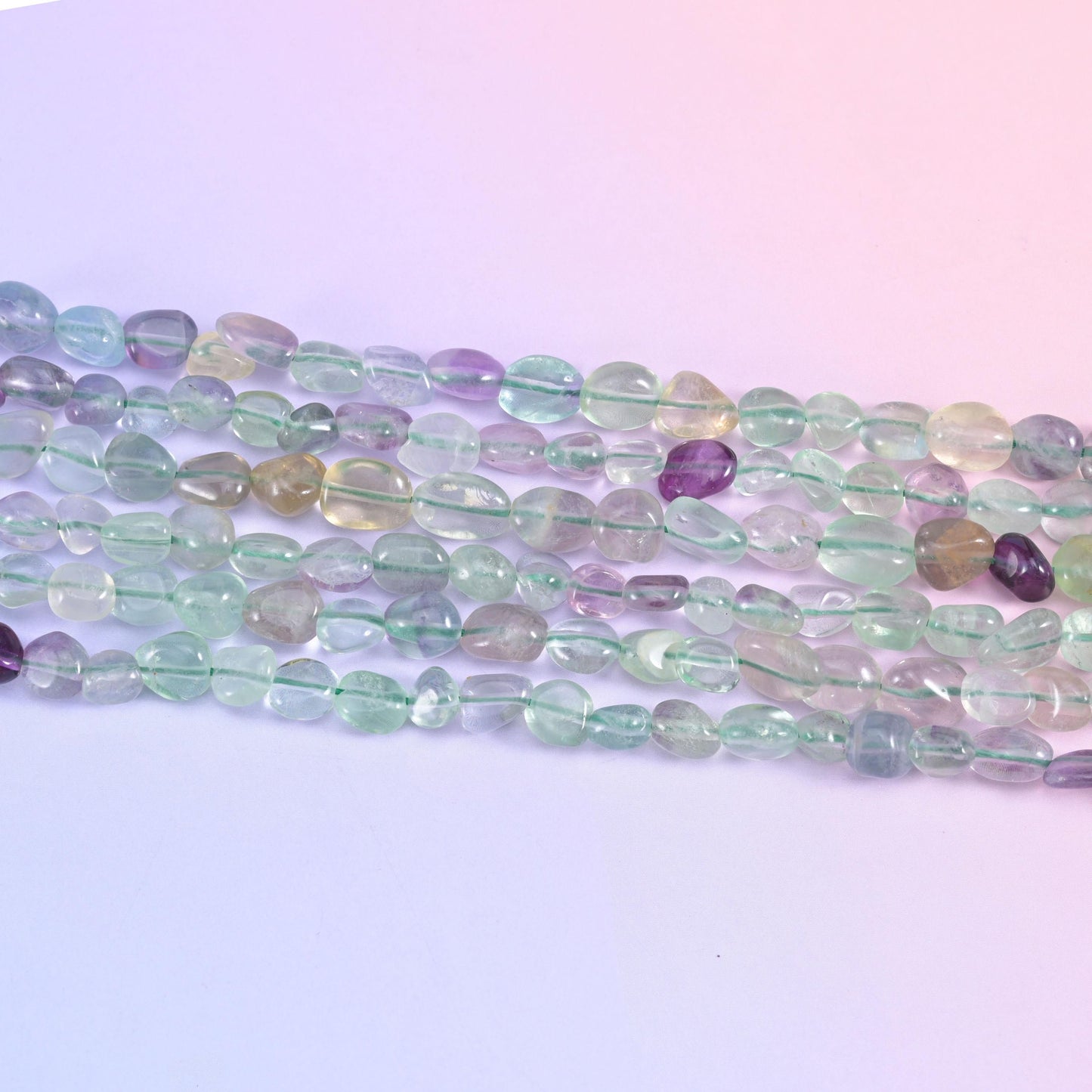 Row of translucent fluorite nuggets in pale green, clear and grape purple