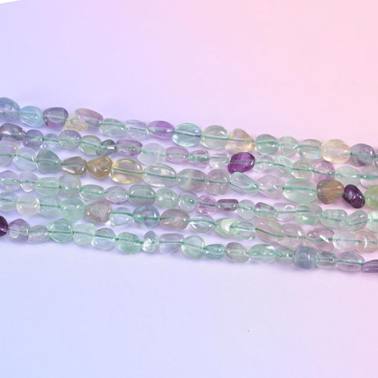 Row of translucent fluorite nuggets in pale green, clear and grape purple