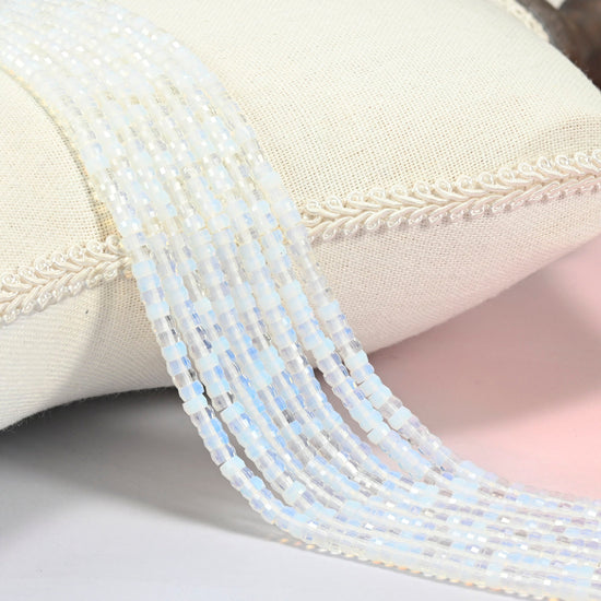 Opalite faceted heishi disc beads 2x4mm, several strands draped over a white cushion
