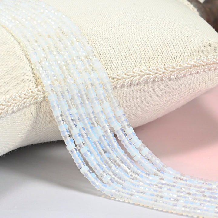 Opalite faceted heishi disc beads 2x4mm, several strands draped over a white cushion